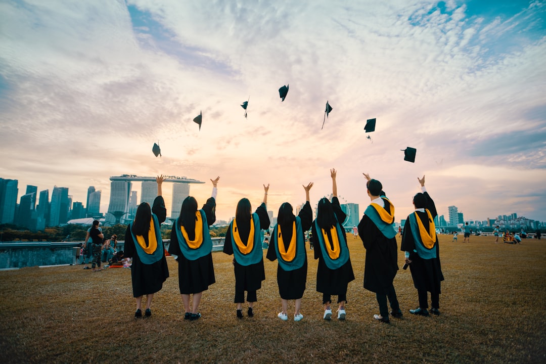 Group of fresh graduates celebrating by throwing their caps into the air at sunset